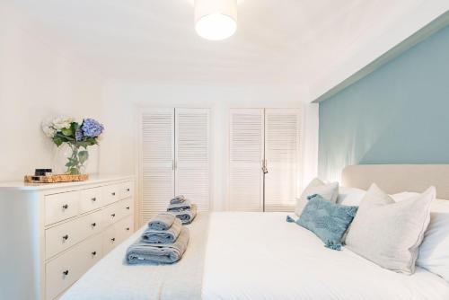 a bedroom with a white bed and a dresser at The Hideout in Sandgate