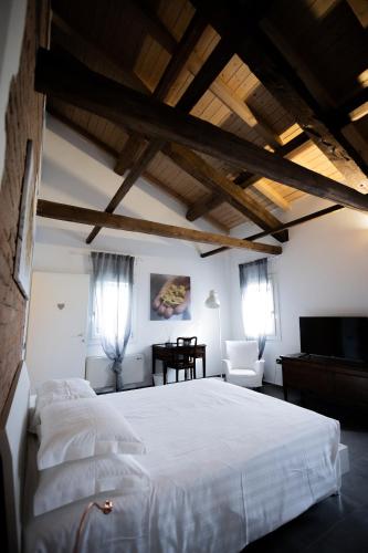 a bedroom with a large white bed and a chair at La Cascina del Balsamico in Gaggio