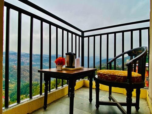 a table and a chair on a balcony with a view at Hotel Aachman Regency with Rooftop Terrace in Shimla