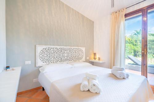 una camera da letto con un letto e asciugamani bianchi di Splendida Villa a Notteri, Spiaggia di Porto Giunco a Notteri