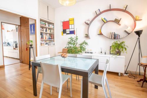 une salle à manger avec une table en verre et des chaises blanches dans l'établissement Les Nocturnes de Chopin, à Tours