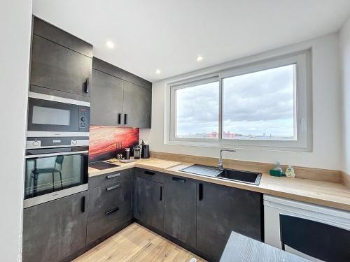 d'une cuisine équipée d'appareils en acier inoxydable et d'une fenêtre. dans l'établissement Le Balcon - Vue sur canal de Brienne, à Toulouse