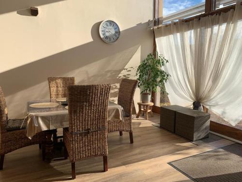 Un comedor con una mesa y sillas y un reloj. en Hébergement de charme et séjour bien-être Auvergne, en Neure