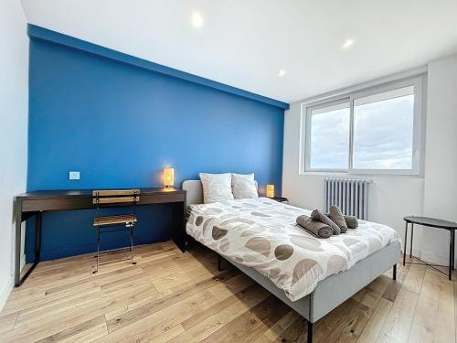 - une chambre dotée d'un mur bleu avec un lit et un bureau dans l'établissement Le Balcon - Vue sur canal de Brienne, à Toulouse
