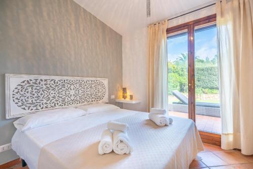 una camera da letto con un letto bianco con due asciugamani di Splendida Villa a Notteri, Spiaggia di Porto Giunco a Notteri