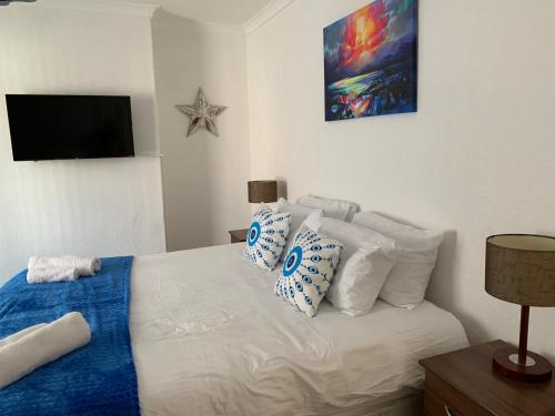 a bedroom with a white bed with pillows and a television at Coronation Place, Durham in Langley Park