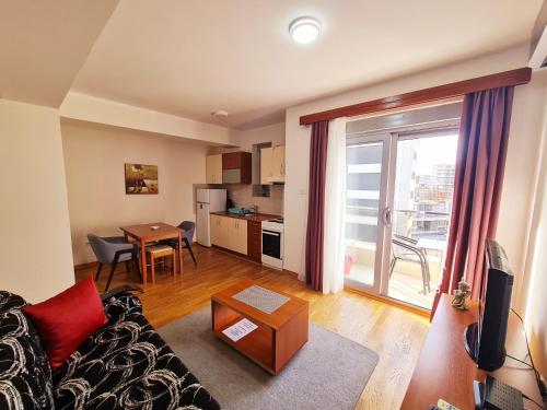 ein Wohnzimmer mit einem Sofa und einem Tisch sowie eine Küche in der Unterkunft Centar New Loki Apartments in Budva
