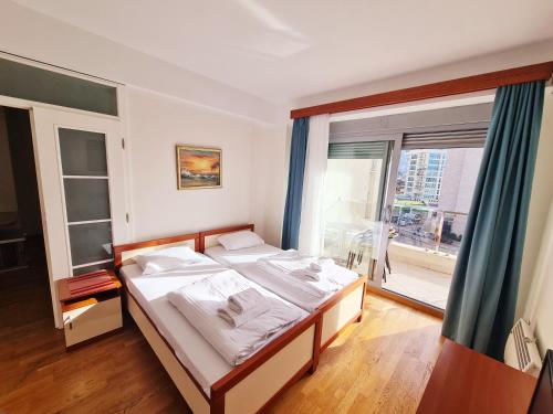 ein Schlafzimmer mit einem Bett und einem großen Fenster in der Unterkunft Centar New Loki Apartments in Budva