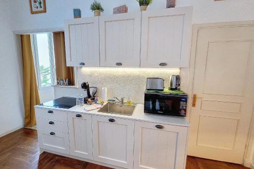 a white kitchen with a sink and a microwave at HENRI CAMILLE REAL ESTATE - Florida - 2 bedrooms close center in Cannes