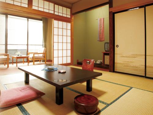 a living room with a coffee table and a living room with windows at Yuzawa Hotel in Yuzawa