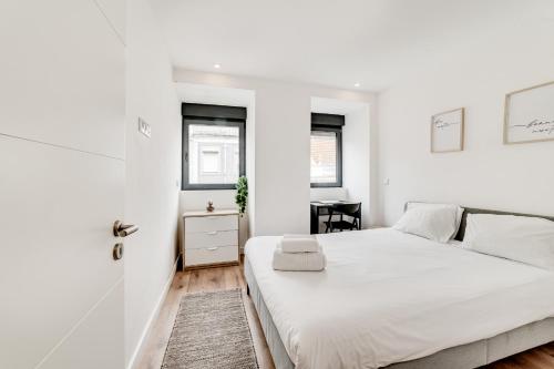 a white bedroom with a bed and a desk at Lapa Stylish Apartments in Lisbon