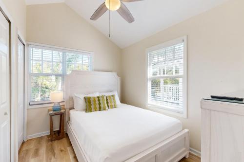 a white bedroom with a bed and two windows at Restful Retreat in Duck Key