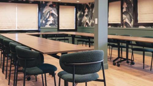 a conference room with wooden tables and green chairs at Uma House by Yurbban South Beach in Miami Beach