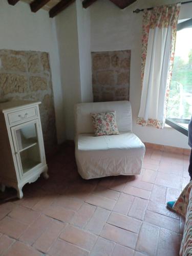 een woonkamer met een witte stoel en een tafel bij Alloggio turistico Il Villino in Maremma in Farnese