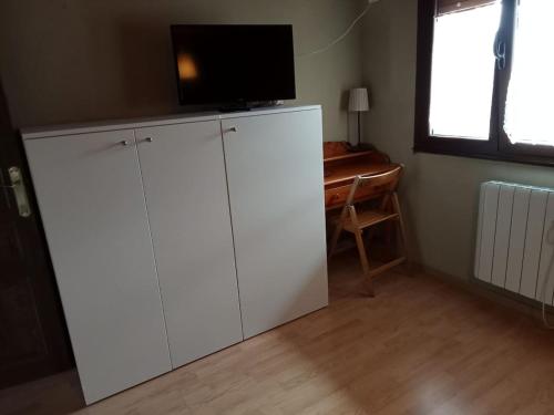a living room with white cabinets and a television on top at One bedroom house with wifi at Bermiego in Bermiego