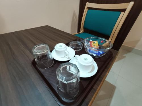 a table with a tray with plates and glasses on it at Hotel Classic Comfort in Bengaluru
