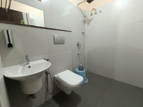 a white bathroom with a sink and a toilet at Hotel Classic Comfort in Bengaluru