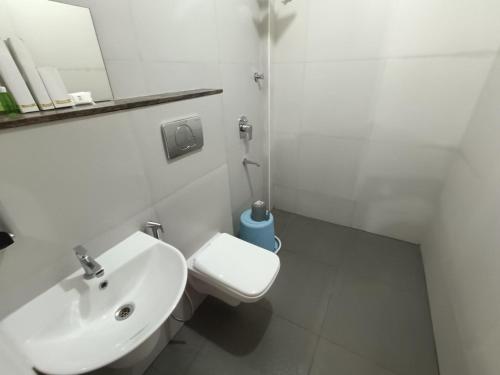 a white bathroom with a sink and a toilet at Hotel Classic Comfort in Bengaluru