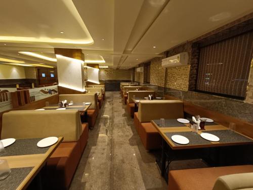 Hotel Classic Comfort في بانغالور: غرفة طعام مع طاولات وكراسي في مطعم