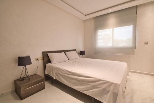 a white bedroom with a bed and a window at The Place To Be - Agadir Centre in Agadir