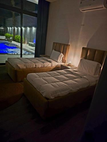two beds sitting in a room with a window at Elysee Villa in Al Rama