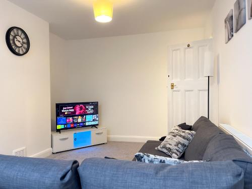 un salon avec un canapé bleu et une télévision dans l'établissement Wembley Stadium, Modern&Cozy Apartment with Garden, à Londres