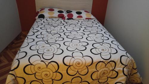a bed with a blanket with flowers on it at Arum Qurpawasi Hospedaje in Cabanaconde