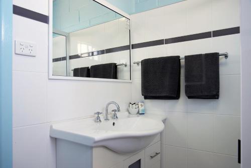 Artesian Motor Inn في Coonamble: حمام أبيض مع حوض ومرآة