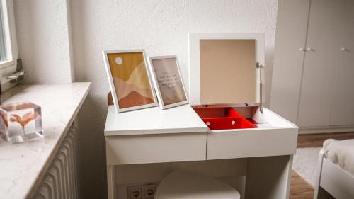 einen weißen Schreibtisch mit zwei Bildern und einem Spiegel in der Unterkunft Exklusive Ferien-Appartements Di Marino in Schönwald