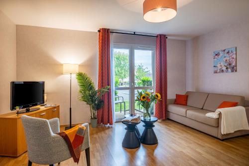 uma sala de estar com um sofá e uma televisão em Résidence Services Seniors DOMITYS - Les Galopins em Trélissac