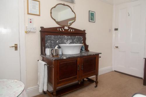 a bathroom with a sink and a mirror on a cabinet at Stockghyll Cottage in Bowness-on-Windermere