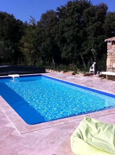 a swimming pool with blue water in a yard at Le carpe noctem suite de charme avec jacuzzi privé in Sérignan-du-Comtat