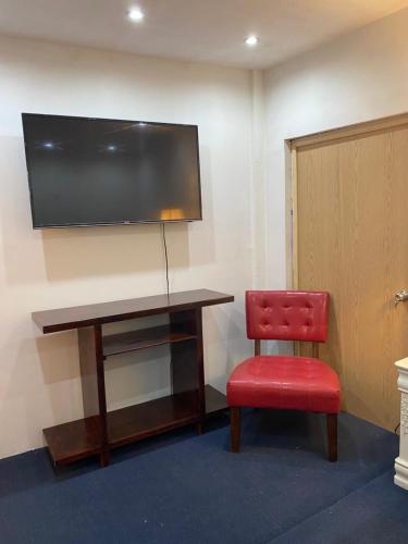 a desk with a red chair and a television on a wall at Renta de habitación/cama matrimonial in Monclova