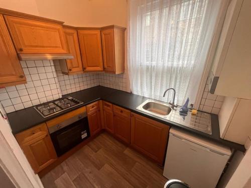 eine kleine Küche mit Holzschränken und einem Waschbecken in der Unterkunft Cosy 1 bed in C.London in London