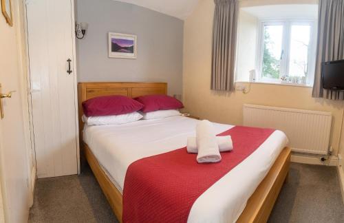 a bedroom with a bed with red and white sheets at Stockghyll Cottage in Bowness-on-Windermere