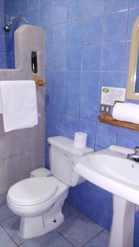 a blue tiled bathroom with a toilet and a sink at Boutique Hotel Casa Orquídeas in San José