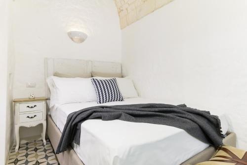 um quarto branco com uma cama e uma mesa de cabeceira em La Dimora del Tempo by Wonderful Italy em Ostuni