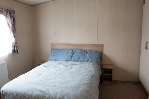 a bedroom with a bed with blue sheets and a window at 2 Bed Caravan For Hire at Golden Sands in Rhyl in Rhyl