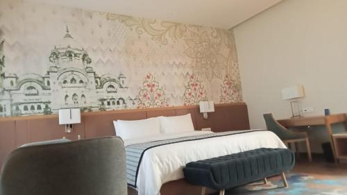 a bedroom with a bed and a desk and a chair at Sarovar Portico, Somnath in Somnath