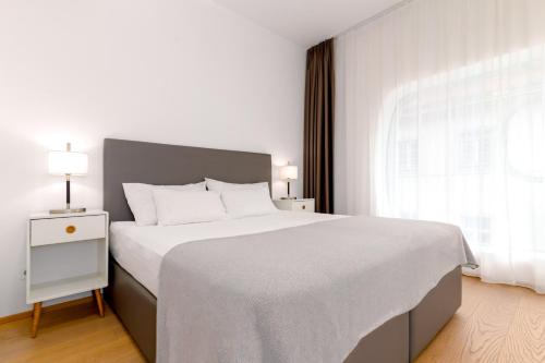 Un dormitorio blanco con una cama grande y una ventana en limehome Graz - Argos by Zaha Hadid, en Graz