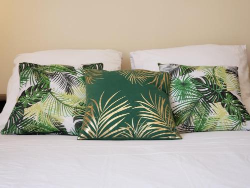 a bed with three pillows with palm leaves at Appart Rouen Centre in Rouen