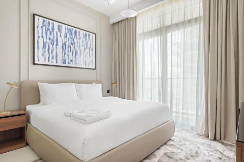 a white bedroom with a large bed and a window at Silkhaus Marina View with Tower's Private Beach in Dubai