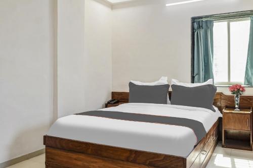 1 dormitorio con cama de madera y ventana en Collection O Hotel Galaxy Executive, en Kharadi