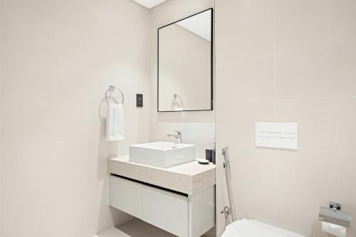 a white bathroom with a sink and a mirror at Silkhaus Marina View with Tower's Private Beach in Dubai