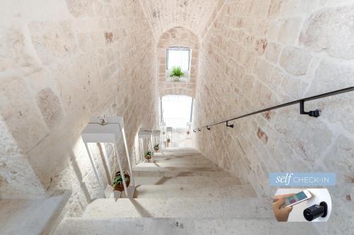 a staircase in a building with a stone wall at Vico Bianco Raro Smart Rooms Collection in Ostuni
