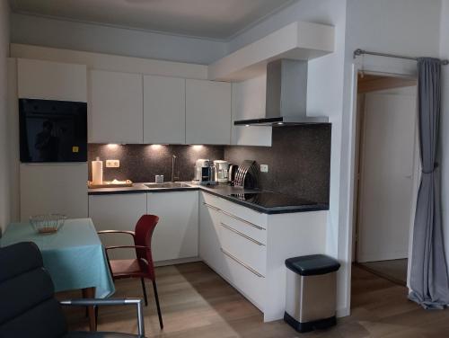 a kitchen with white cabinets and a table with chairs at Aldenhof Appartementen in Maastricht