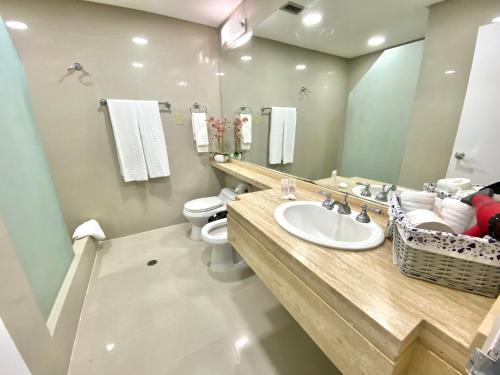 uma casa de banho com um lavatório, um WC e um espelho. em Suite HotelCCT em Caracas