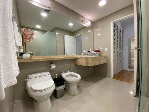 a bathroom with a toilet and a sink and a mirror at Suite HotelCCT in Caracas