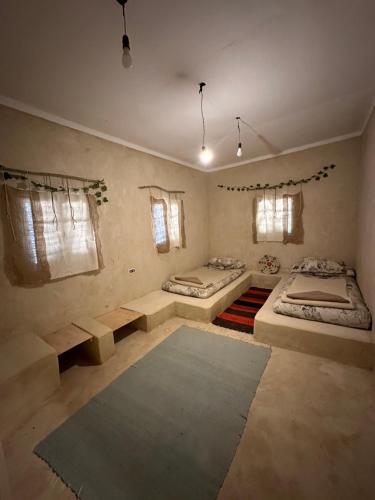 a room with two beds and a rug at Thraa - ثراء in Siwa