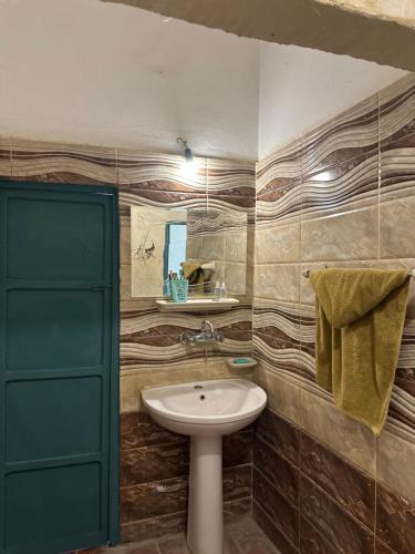 ein Badezimmer mit einem Waschbecken und einer grünen Tür in der Unterkunft Thraa - ثراء in Siwa